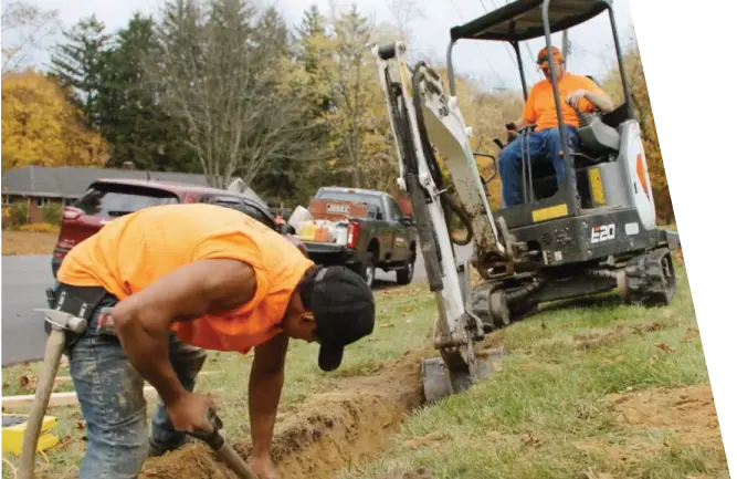 Workers digging trench in front yard for drainage installation